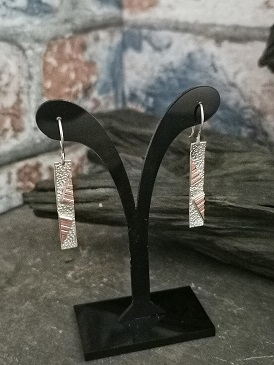 earrings displayed on plastic stand with wood in the back ground- geometric handmade earrings