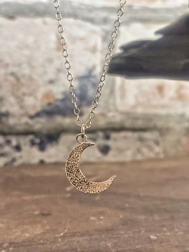 necklace hanging in front of wall - textured moon necklace