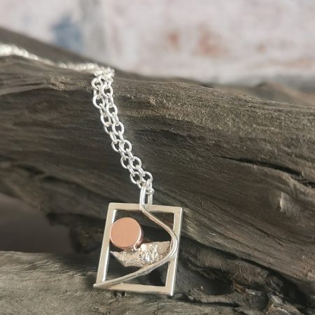 necklace displayed on bog oak - handmade sterling silver sunrise necklace