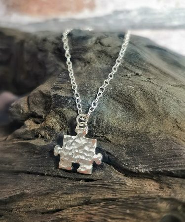 neckace displayed on bog aok - sterling silver puzzle piece necklace